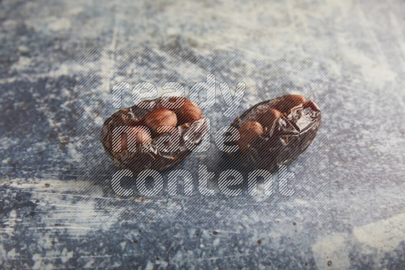 two hazelnuts stuffed madjoul dates on a rustic blue background