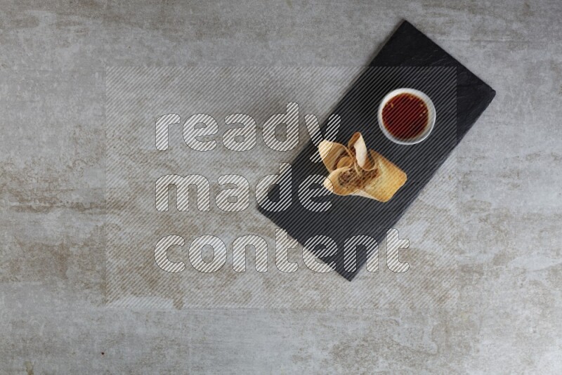 wonton cups with soy sauce ramkin on rectangle slate on grey textured counter top