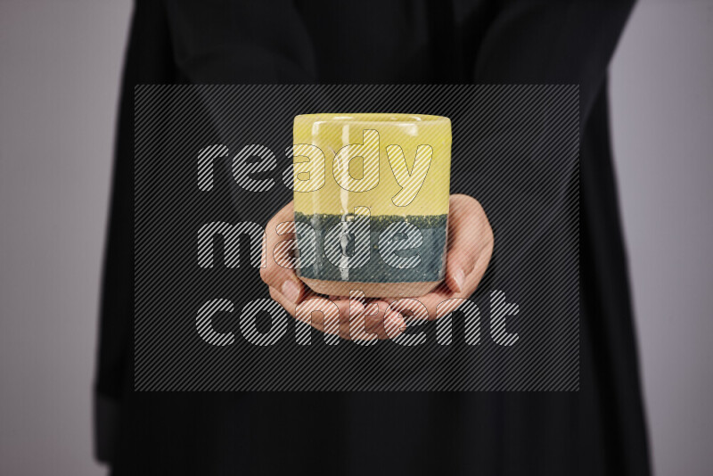 A woman in black abaya holding different pottery essentials in different positions