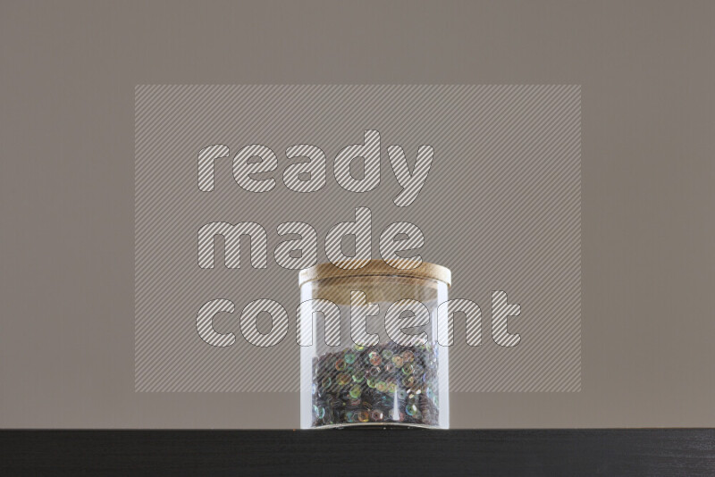 Sequins in a glass jar on black background