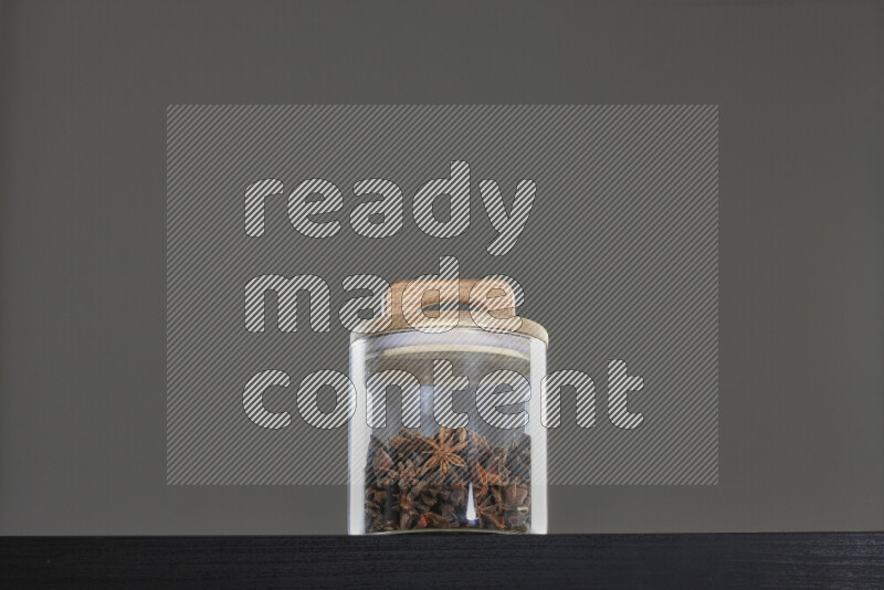 Star anise in a glass jar on black background