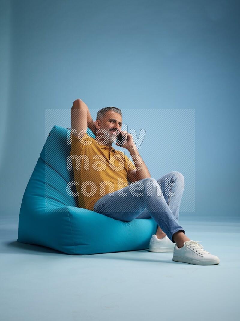 A man sitting on a blue beanbag and talking on the phone