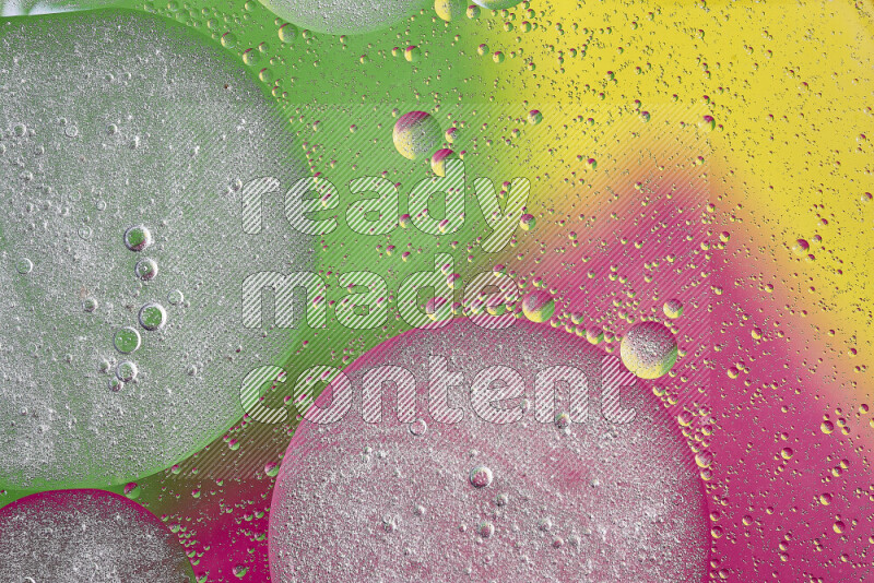 Close-ups of abstract oil bubbles on water surface in shades of yellow, green and pink