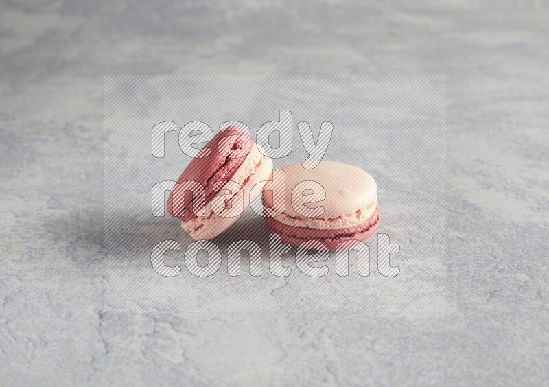 45º Shot of two Pink Litchi Raspberry macarons  on white  marble background