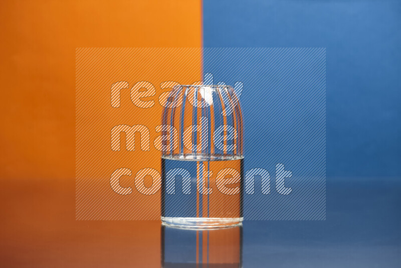 The image features a clear glassware filled with water, set against orange and blue background