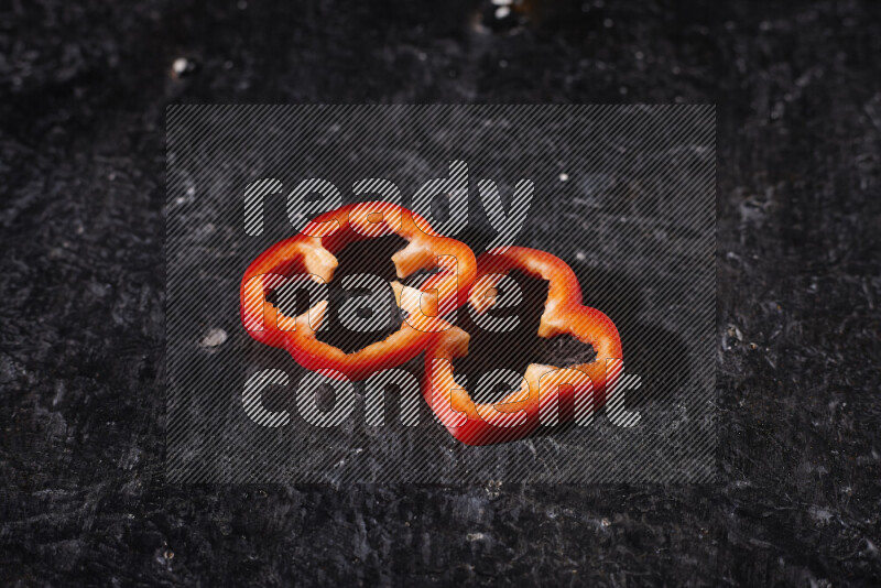 Red bell pepper slices on black background