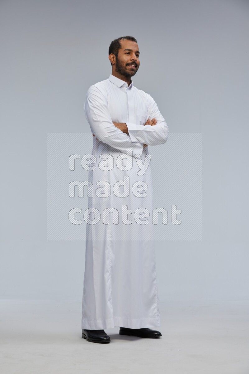 Saudi man wearing Thob standing with crossed arms on Gray background