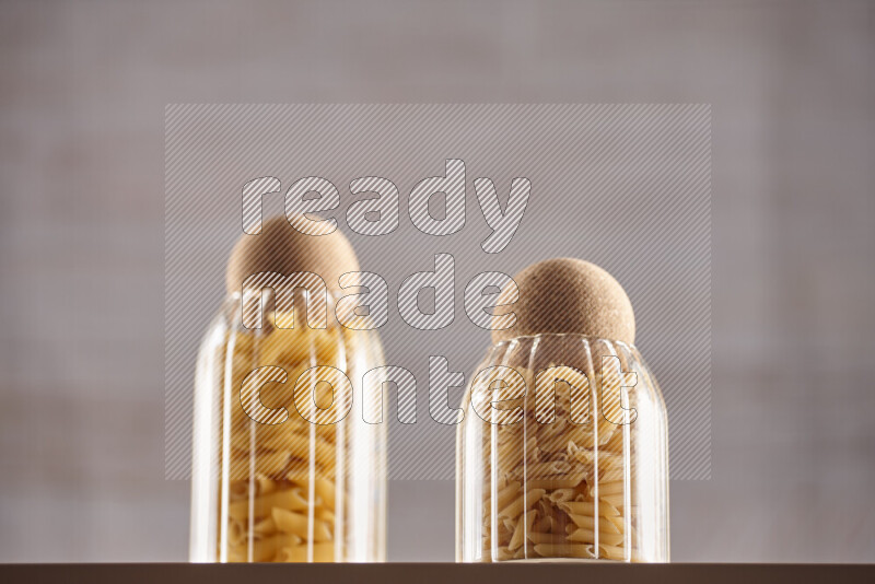 Raw pasta in glass jars on beige background