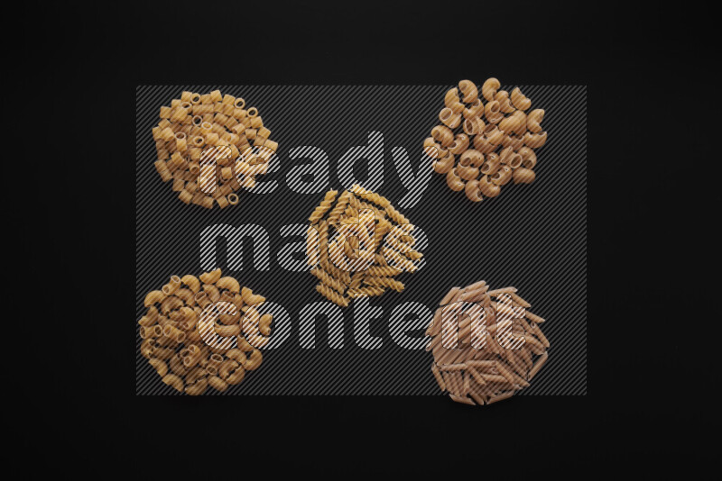 Different pasta types in bunches on black background