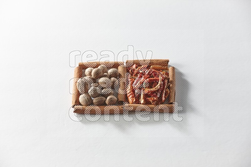 مربعان من أعواد القرفة ممتلئان بالفلفل الحار المجفف وجوزة الطيب علي خلفية بيضاء