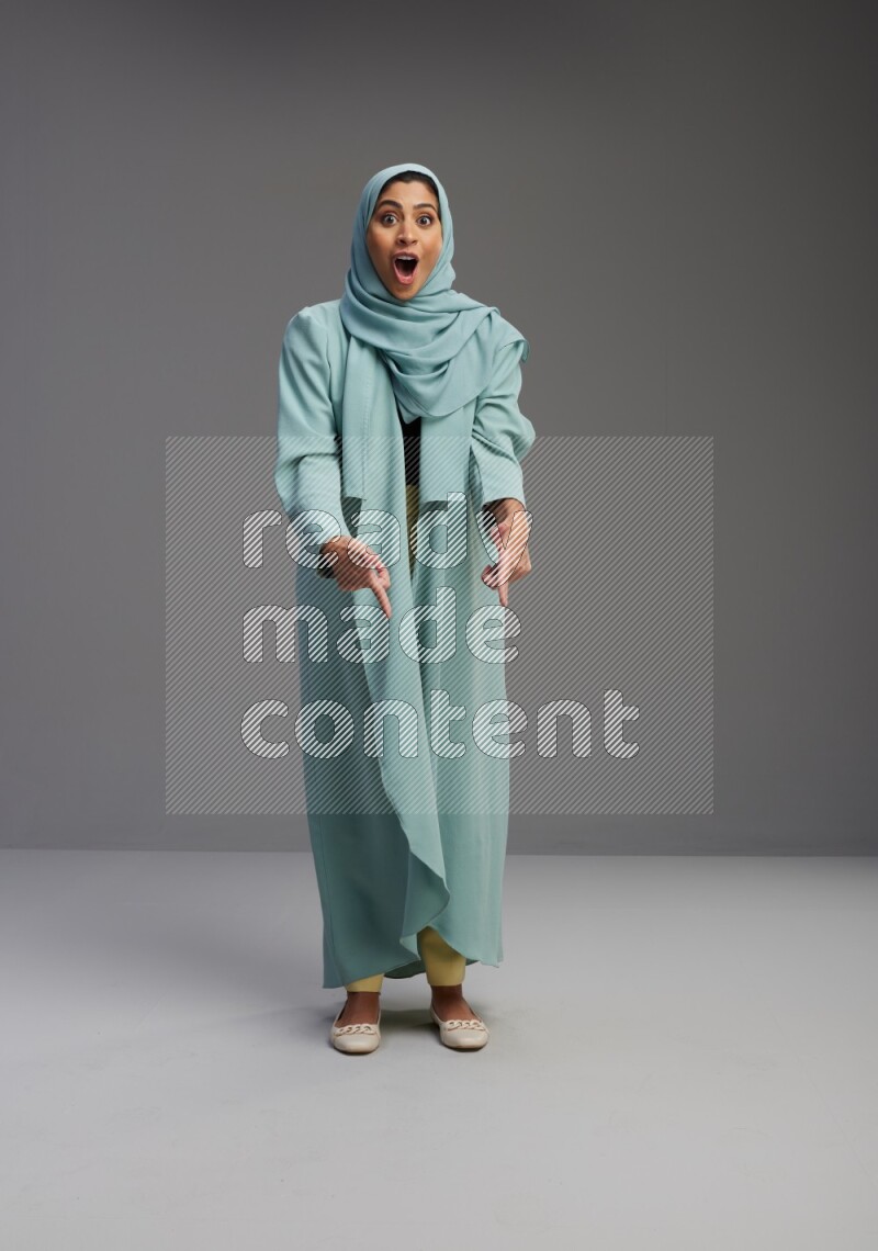 Saudi Woman wearing Abaya standing interacting with the camera on Gray background
