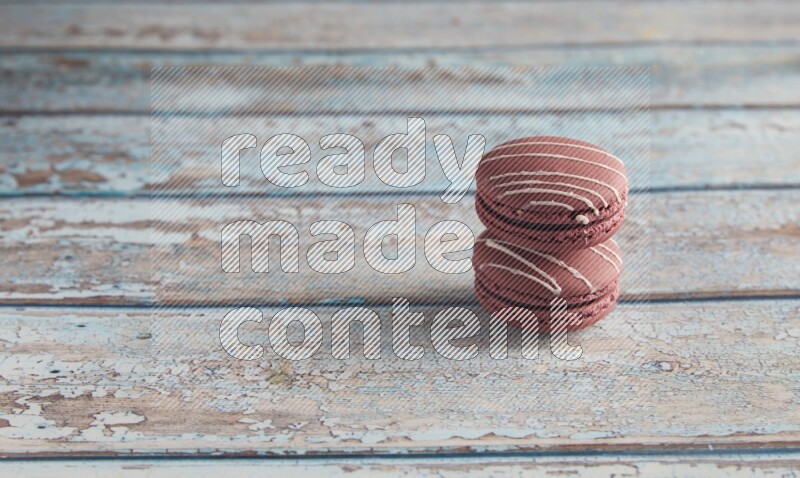 45º Shot of two Red Poppy Flower macarons on light blue wooden background