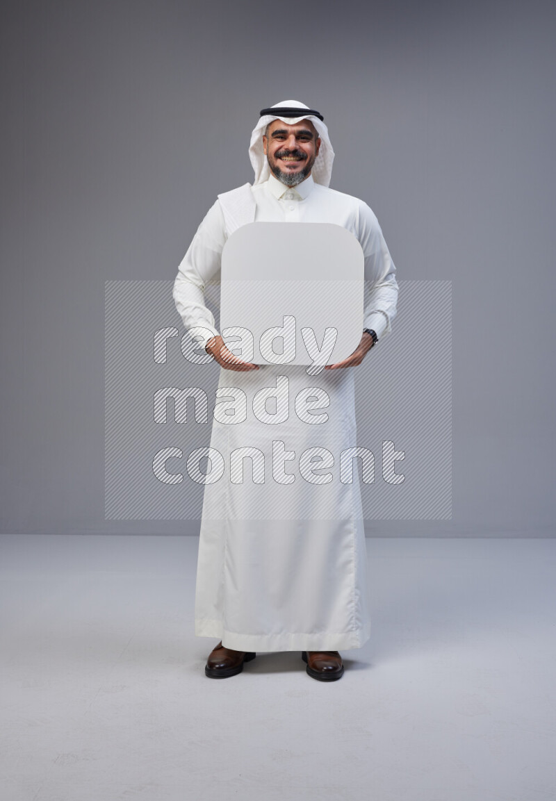 Saudi man Wearing Thob and white Shomag standing holding social media sign on Gray background