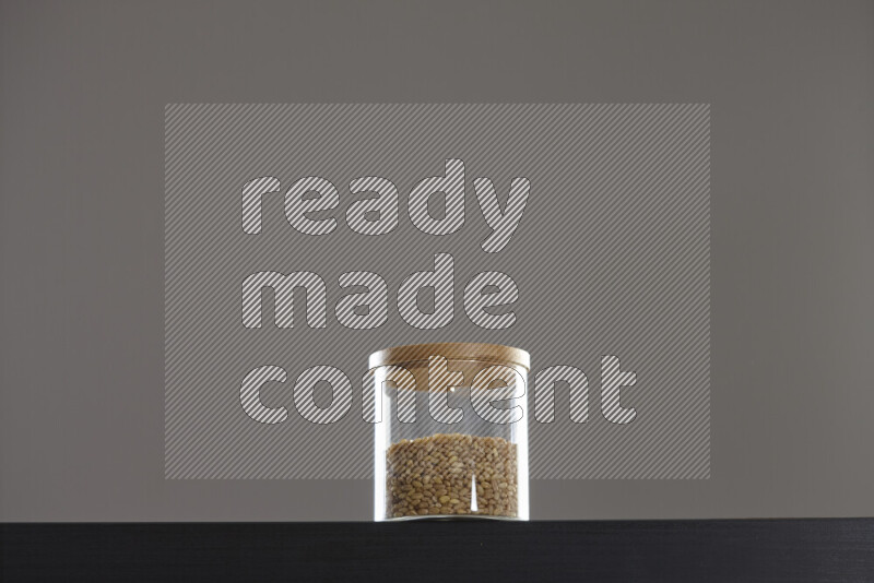 Hulled wheat in a glass jar on black background
