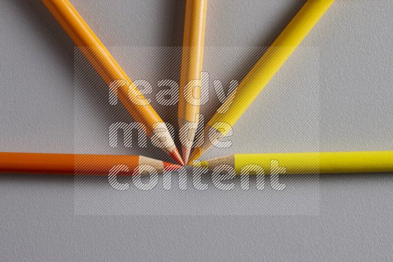 An arrangement of colored pencils in different colors on grey background