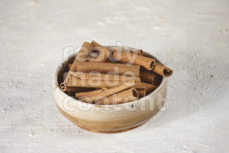 Cinnamon sticks in a ceramic bowl in different angles on white background