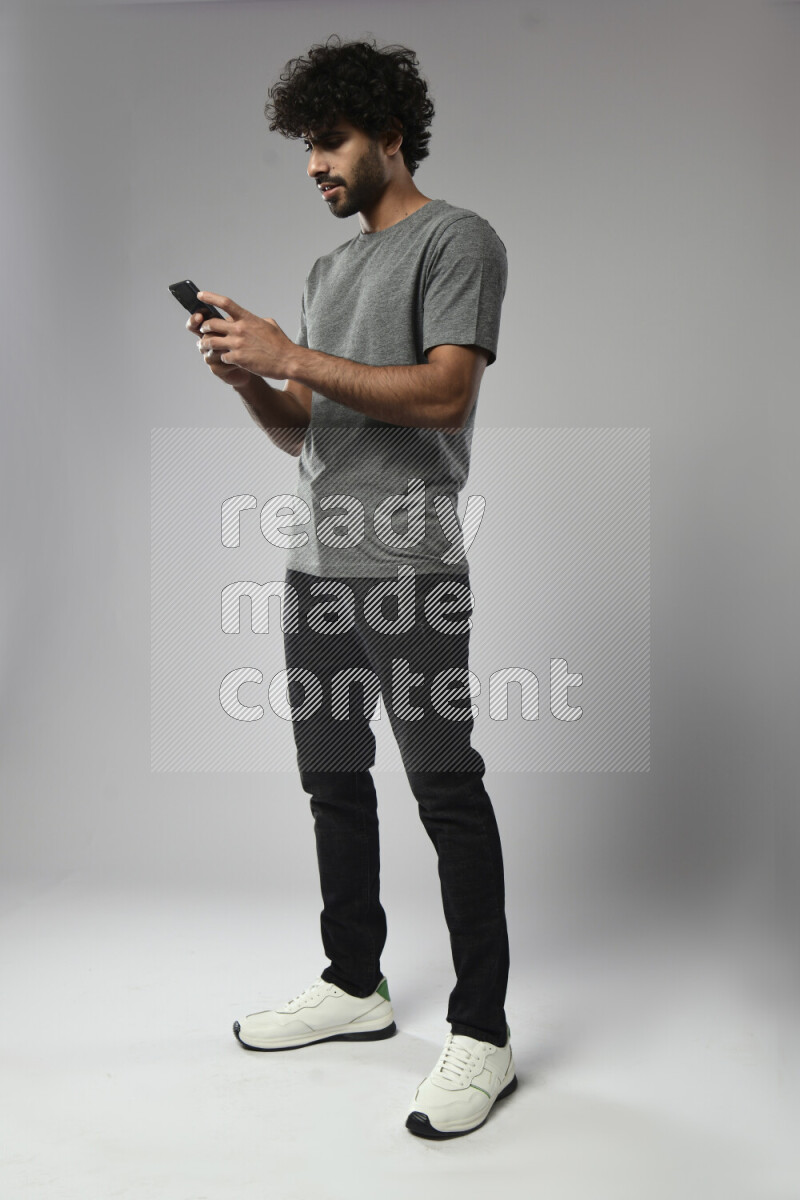 A man wearing casual standing and texting on the phone on white background