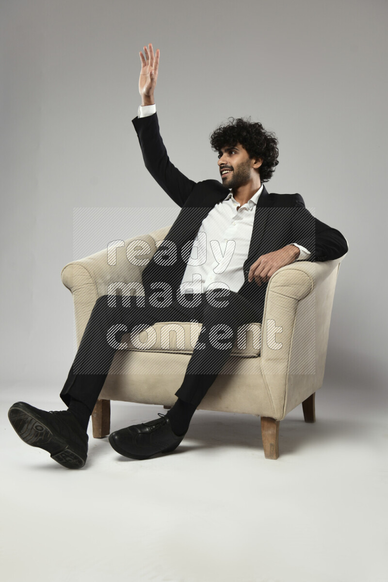 A man wearing formal sitting on a chair making a hand gesture on white background