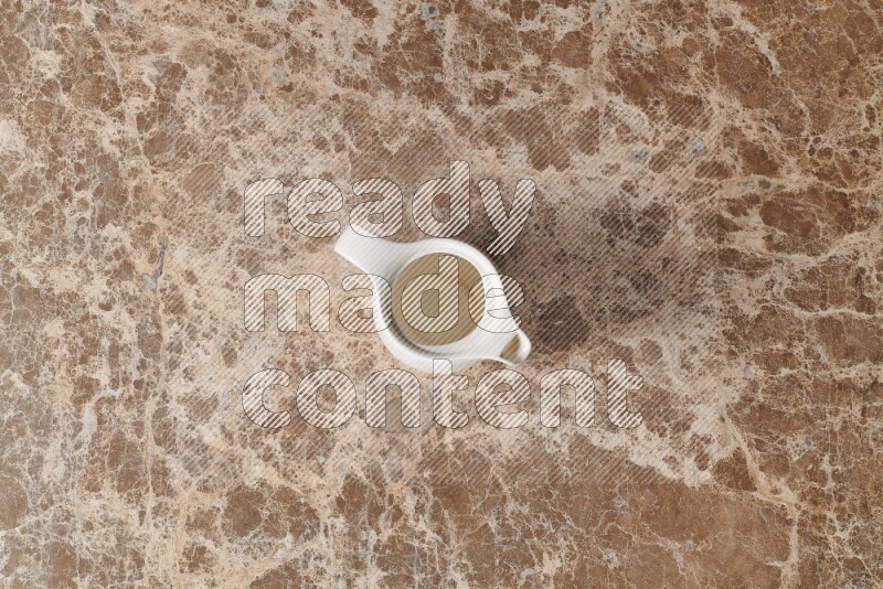 A ceramic milk jug on beige marble background