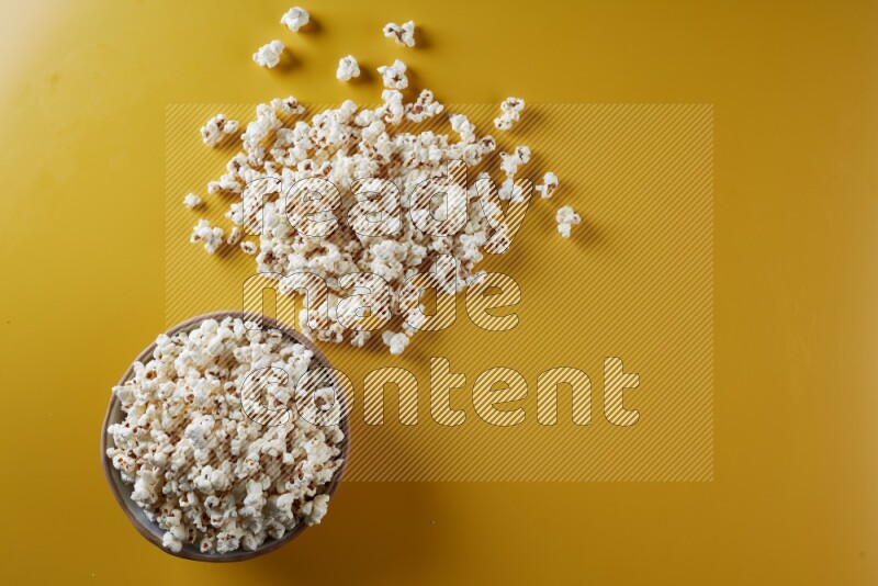 A brown pottery bowl full of popcorn with popcorn beside it on a yellow background in different angles