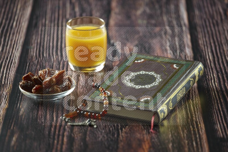 Quran with dates, prayer beads and different drinks all placed on wooden background