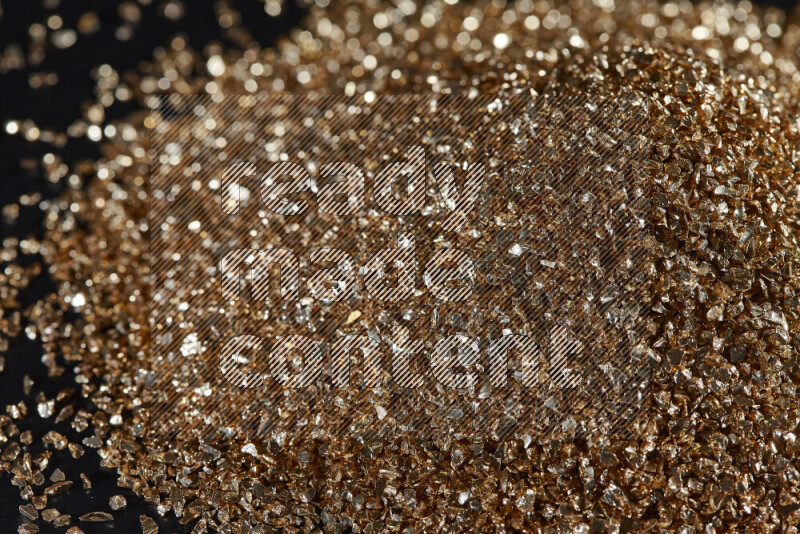 Gold shimmering fragments of glass scattered on a black background