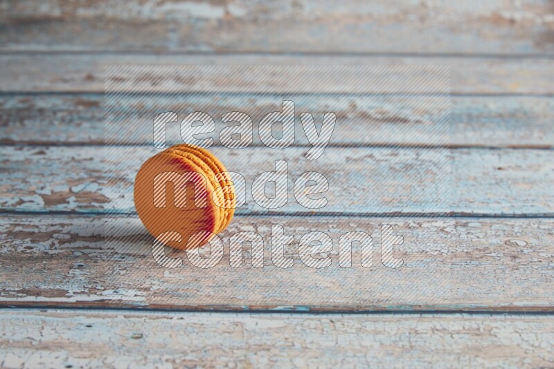 45º Shot of Orange Exotic macaron on light blue wooden background