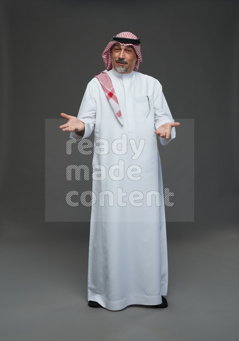 Saudi man with shomag Standing Interacting with the camera on gray background