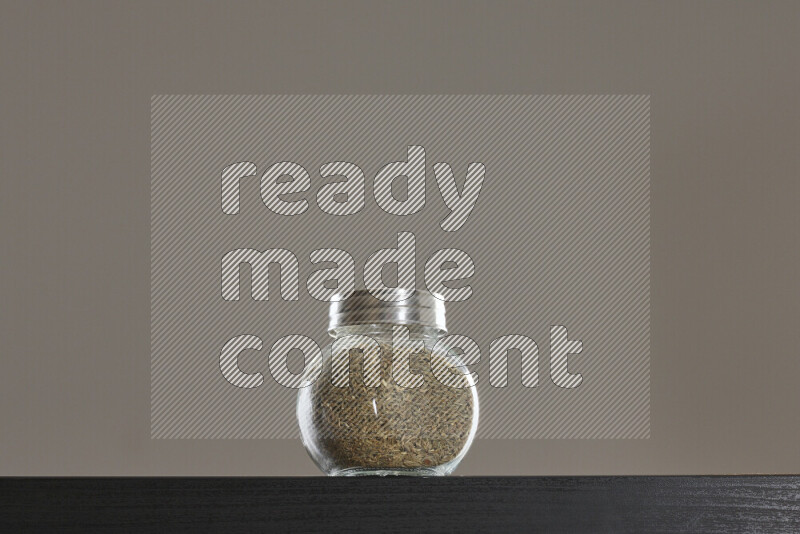 Cumin in a glass jar on black background