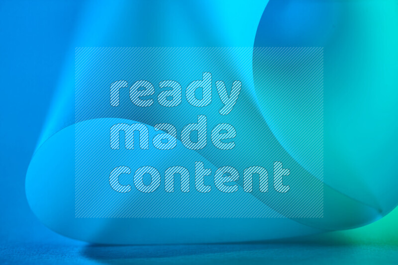 An abstract art piece displaying smooth curves in green and blue gradients created by colored light