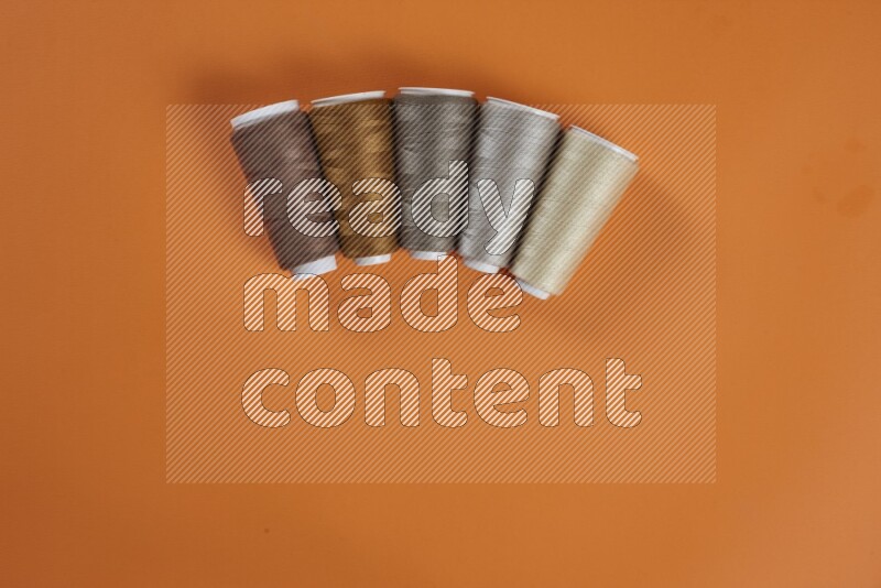 A brown collection of sewing and tailoring tools arranged on a orange background