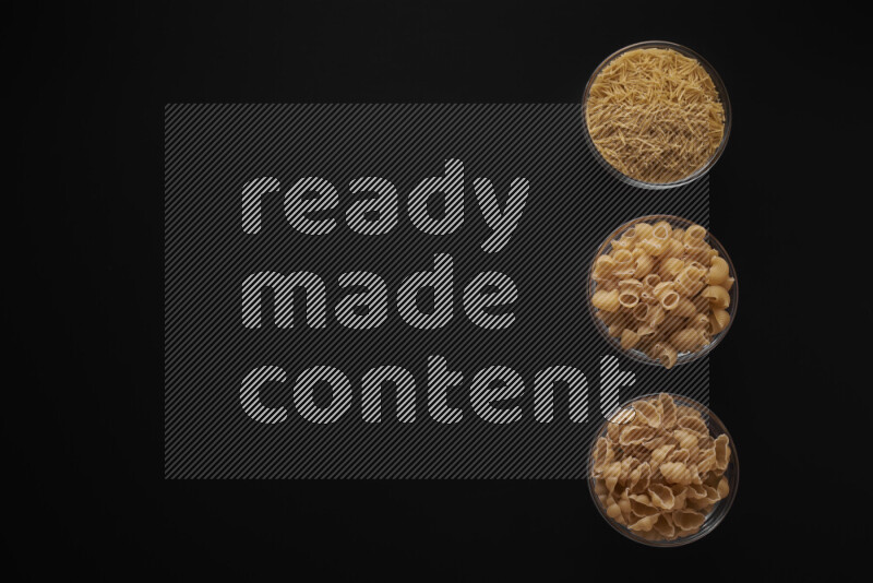 Different pasta types in 3 glass bowls on black background