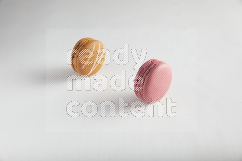 45º Shot of of two assorted Brown Irish Cream, and Pink Raspberry macarons on white background