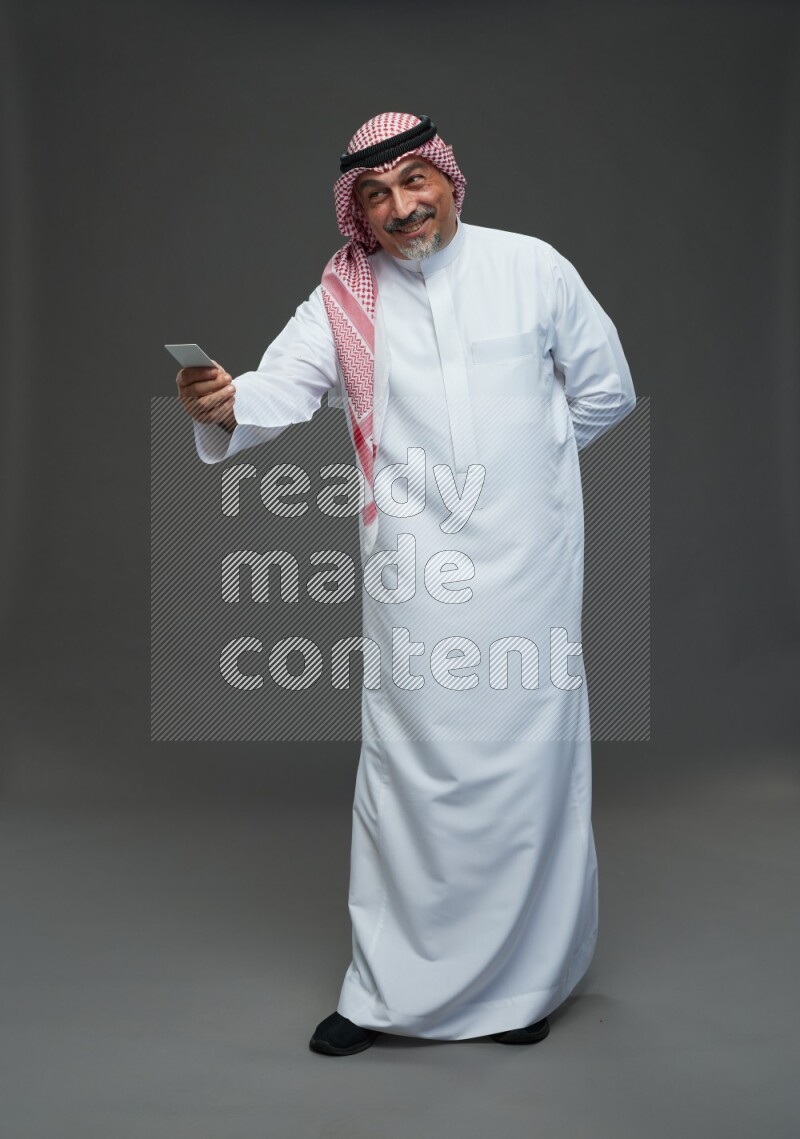 Saudi man with shomag Standing holding ATM card on gray background