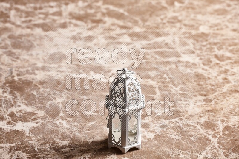 A candle lantern on beige marble background