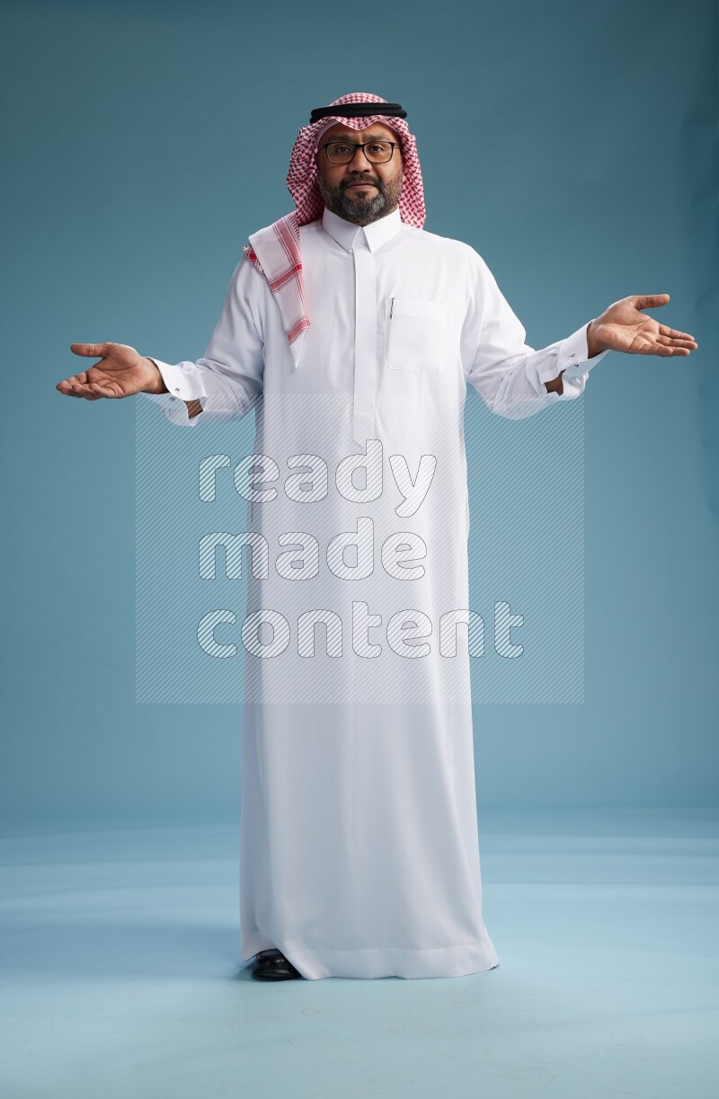 Saudi Man with shimag Standing Interacting with the camera on blue background