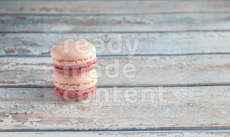 45º Shot of two Pink Litchi Raspberry macarons on light blue wooden background