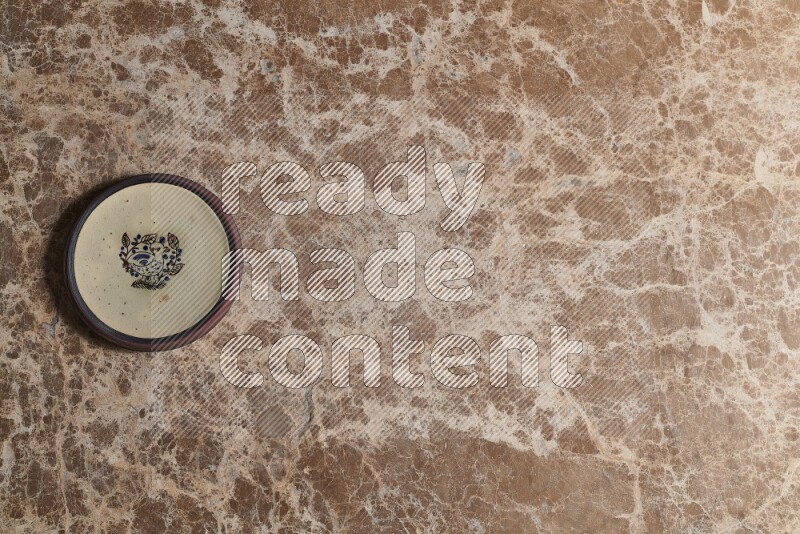 A decorative pottery plate on beige marble background