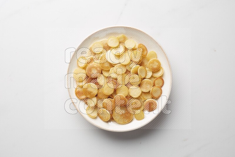 Top-view shot of plain cereal pancakes in a round bowl on white background