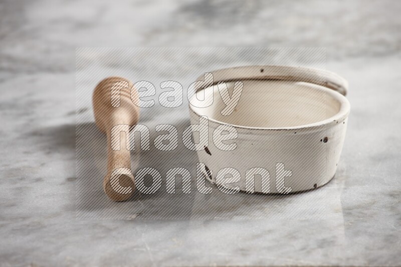 White pottery bowl with wooden honey dipper on the side on grey marble background