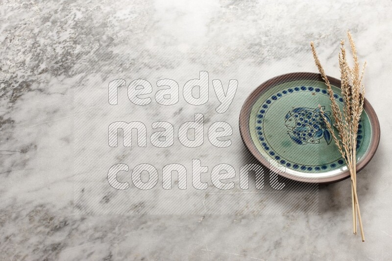 Wheat stalks on decorative pottery plate on grey marble background