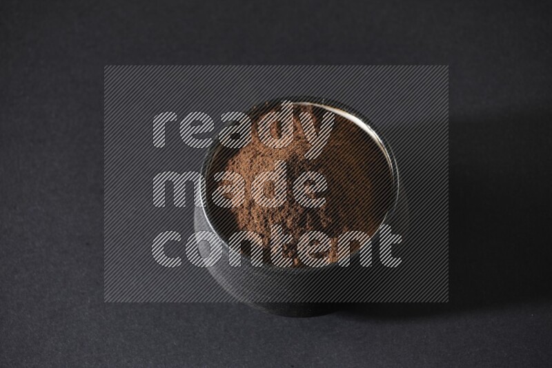 وعاء فخاري أسود ممتلئ ببودرة القرنفل علي خلفية سوداء