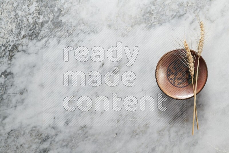 Wheat stalks on decorative pottery plate on grey marble background