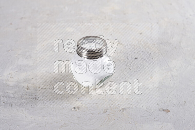 A glass jar full of fine table salt on white background