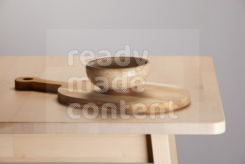 multi colored bowl placed on a  wooden oval cutting board on the edge of wooden table