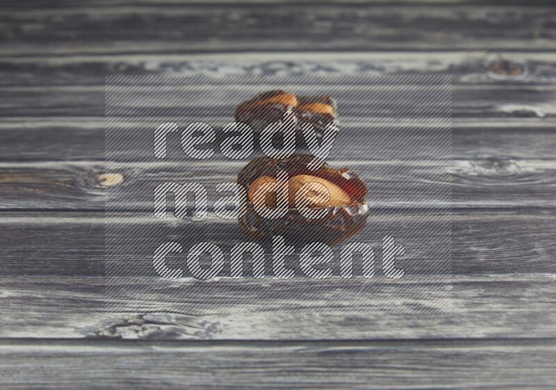 two almond stuffed madjoul dates on a wooden grey background