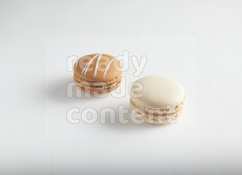 45º Shot of of two assorted Brown Irish Cream, and White Caramel fleur de sel macarons on white background