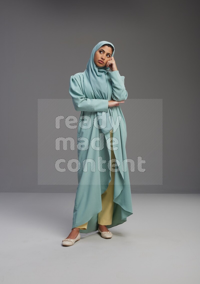 Saudi Woman wearing Abaya standing interacting with the camera on Gray background