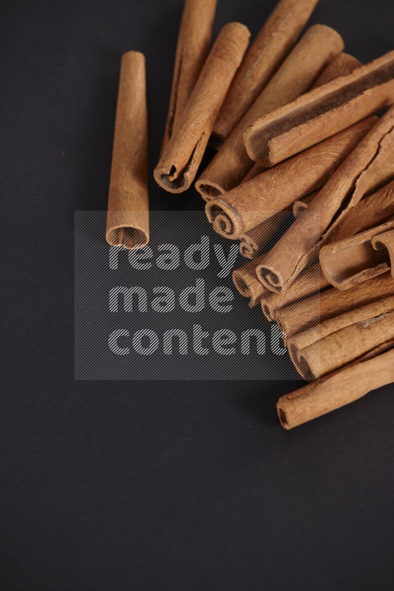 Cinnamon sticks stacked on black flooring