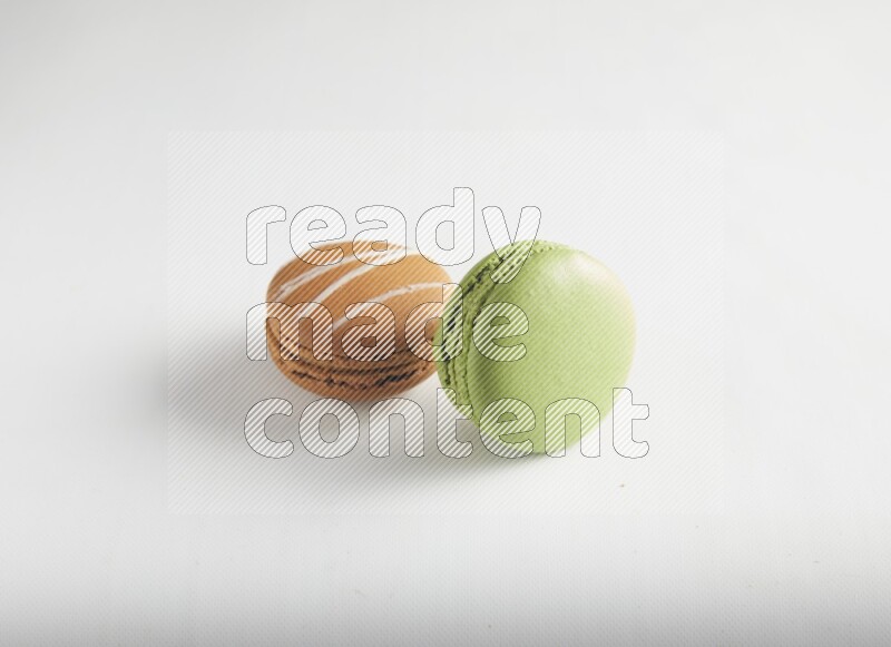 45º Shot of of two assorted Brown Irish Cream, and Green Pistachio macarons on white background
